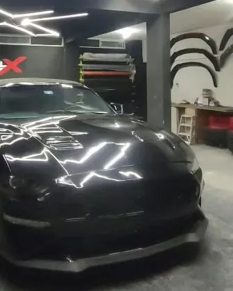 Ford Mustang negro con reflejos de las luces del taller