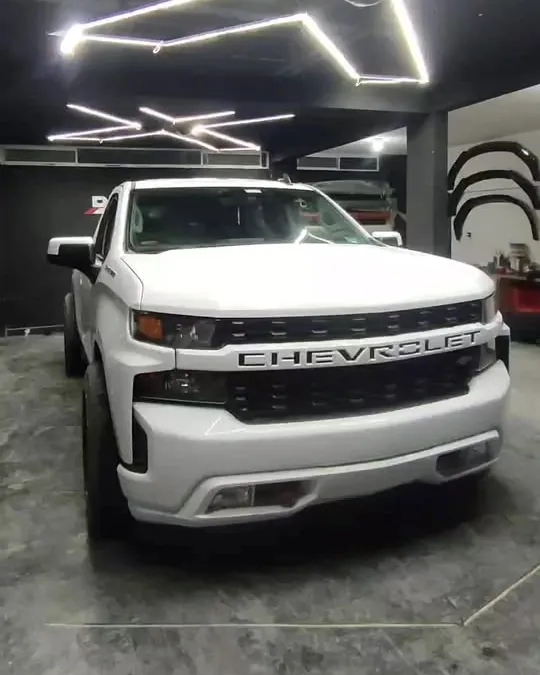 Chevrolet Silverado blanca bajo las luces del taller