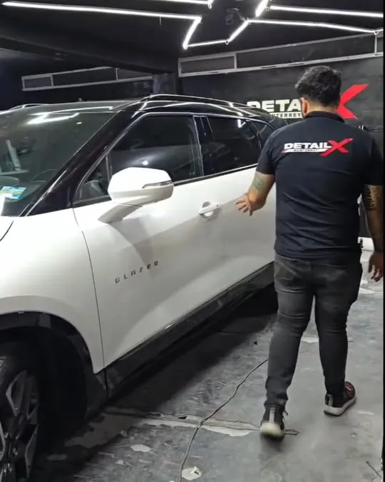 Técnico de Detail X aplicando vinil en una camioneta blanca